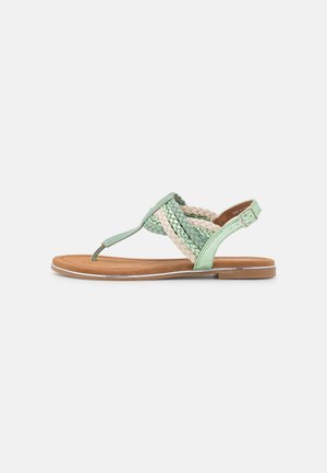 Flad sandal med flettede mintgrønne og beige remme, tåstrop, justerbar ankelrem og en tan fodseng med tynd sål.