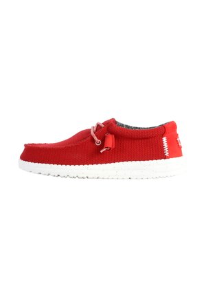 Zapato de tela rojo sin cordones con suela blanca, tejido texturizado, costuras en contraste y un interior de forro gris claro. Cuenta con un lazo decorativo.