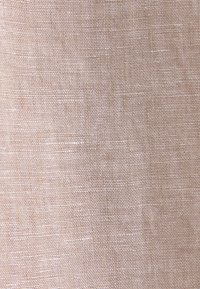 Tissu en lin beige à armure toile serrée et régulière montrant de légères variations naturelles et des plis subtils.