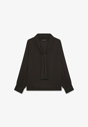 Blouse noire en tissu léger avec un col à nouer, des manches longues et un motif à pois subtil. Présente des poignets froncés pour un détail.