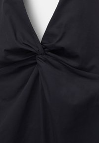Maillot de bain ou body en tissu noir avec un décolleté en V profond et un détail de nœud torsadé au centre devant.