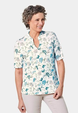 Kurzärmelige Bluse mit floralem Muster in Blau und Grau auf hellem Hintergrund, mit einem V-Ausschnitt und glatter Stofftextur.
