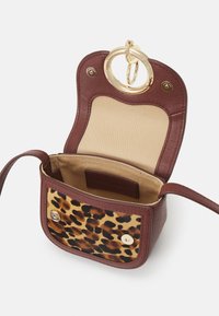 Kožená kabelka s hlubokým burgundským tělem a přední částí s leopardím potiskem. Obsahuje zlatou rukojeť ve tvaru kroužku a měkký béžový interiér.