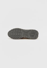 Grey textured outsole with a patterned tread, featuring rectangular and circular indentations for grip and durability.