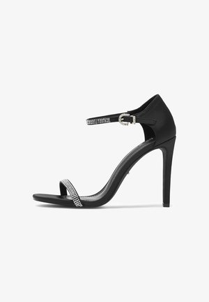 Fekete, magas sarkú szandál sima selyemfényű felülettel, nyitott orrú kialakítással, kristályokkal díszített bokapánttal és vékony stiletto sarokkal.
