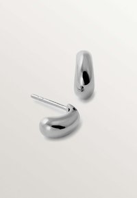 Pendientes de metal plateado con un diseño suave y redondeado. Un pendiente tiene una forma curvada, mientras que el otro es más aerodinámico.