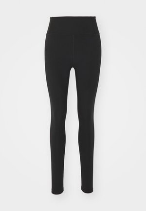 Leggings noires taille haute en matériau extensible, avec une texture lisse et un design ajusté, s'étendant jusqu'à la cheville sans motifs.