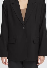 Blazer noir avec un bouton unique, des revers crantés, deux poches avant et une coupe décontractée. Tissu lisse avec une finition mate.