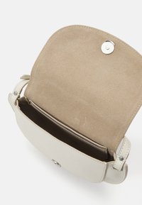 Heled beige nahkakott ümmarguse kujuga, magnetkinnitusega ja pehme seemisnahast sisuga. Omab reguleeritava rihma riistu.
