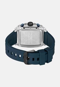 Montre de police rectangulaire avec un boîtier en acier inoxydable argenté, un bracelet en silicone bleu, un fond gravé et des boutons d'accent bleu.