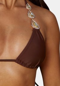 Top bikini a triangolo marrone con spallina decorativa arricchita da gemme a forma di goccia in oro e blu, e dettagli a ruches testurizzati.