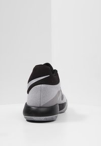 Szare i czarne buty sportowe z teksturowanym wierzchem, wyściełanym kołnierzem oraz gumową podeszwą z wzorzystym bieżnikiem. Srebrne akcenty z logo.