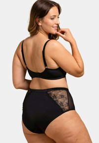 Ensemble de soutien-gorge noir à bordure en dentelle et de culottes taille haute, présentant des motifs floraux sur les côtés, des bretelles ajustables et une texture lisse.