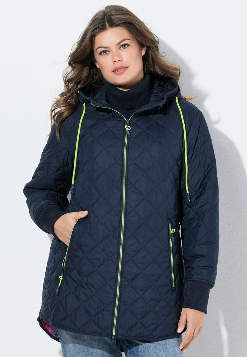 Giubbotto imbottito blu navy con cappuccio, con vivaci accenti verdi e cerniere. Include tasche laterali e polsini a costine per maggiore comfort.
