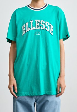 T-shirt turquoise avec col rond et bordures côtelées rayées. Présente un logo "ELLESSE" pelucheux en blanc et bleu. Coupe ample avec manches courtes.