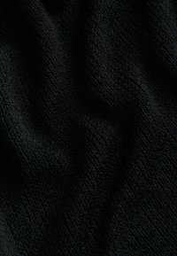 Gros plan sur un tissu éponge noir montrant une surface texturée à boucles et des plis subtils.
