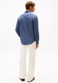 Blauw geblokte overhemd met lange mouwen en knoopmanchetten, gecombineerd met witte brede broek met voorzakken en een ontspannen pasvorm.