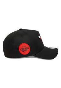 Căciulă de baseball neagră cu un logo brodat al echipei Chicago Bulls pe față și o insignă roșie circulară pe lateral cu detalii textuale.