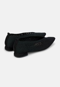 Bailarinas negras con una parte superior de malla y un patrón texturizado, y un tacón bajo. La punta es afilada y el tacón está hecho de ante negro.