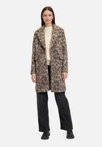 Płaszcz w panterkę z miękkiego materiału, z szerokim kołnierzem, dwiema przednimi kieszeniami i luźnym krojem, założony na lekki sweter i ciemne dżinsy.