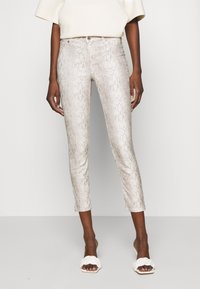Snake print jeans in light beige, fitted design, mid-rise waist, cropped length, with button closure and front pockets. Smooth texture.