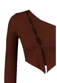 Ruskohertainen ruskea crop-top pitkillä hihoilla, jossa on ainutlaatuinen leikkaus yksityiskohtana kaulan ympärillä ja vartalonmyötäinen muotoilu.