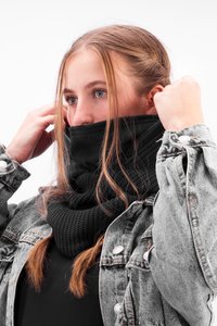 Black knitted cowl neck scarf layered under a denim jacket, featuring a textured design and a seamless finish at the top edge.