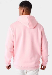 Felpa con cappuccio rosa realizzata in tessuto morbido. Presenta una tasca a marsupio, polsini e orlo a coste, con una vestibilità comoda e rilassata.