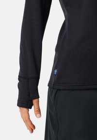 Musta pitkähihaine urheilupaita, jossa on istuva malli. Paidassa on peukaloaukot hihansuissa, teksturoitu kangas ja pieni sininen ja keltainen lippuaksentti.