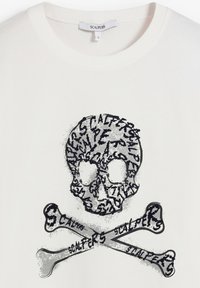 Camiseta de algodón blanca con un diseño de calavera negra hecho de texto, con huesos cruzados debajo. Cuello redondo simple y ajuste relajado.