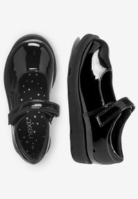 Zwarte gepatineerde leren schoenen met een ronde neus, klittenband en een getextureerde zwarte inlegzool met sterrenpatroon. Dikke rubberen zool zorgt voor duurzaamheid.