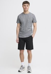 Grå heather crew-neck t-shirt, sorte shorts, hvide sokker og grå sneakers. Stoffet er let og har en glat tekstur samt en afslappet pasform.