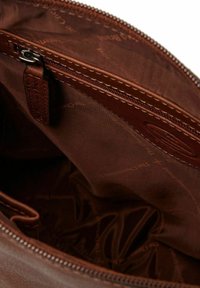Intérieur d'un sac en cuir marron avec une texture lisse, doté d'une fermeture éclair et d'une doublure douce. Le motif intérieur présente le logo de la marque dans une impression subtile.