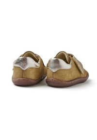 Par de pequeñas botas de ante marrón para bebés con acentos metálicos plateados en el tacón y suelas de goma suave, vistas desde atrás sobre un fondo blanco.