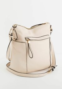 Sæk i beige struktureret læder med sort kant. Har en frontlomme med lynlås og en justerbar rem med hardware i guld tone.