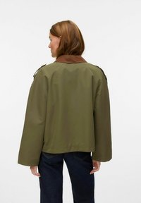 Zeleni oversized jakna z rjavim ovratnikom, ki ima gladko teksturo in ohlapne rokave; prikazana na enobarvnem belem ozadju.