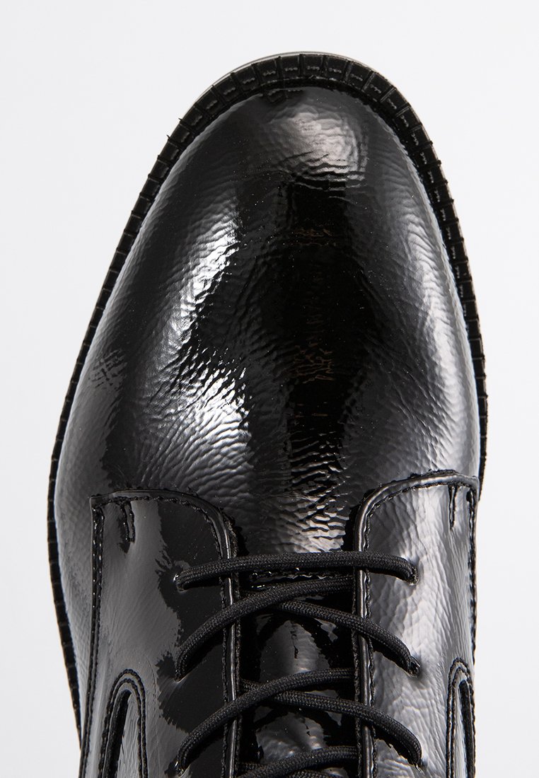 Zwarte gepatenteerde leren schoen met een gestructureerd oppervlak, ronde neus en zwarte veters. Gestikte accenten en een laagprofiel rubberen zool zijn zichtbaar.