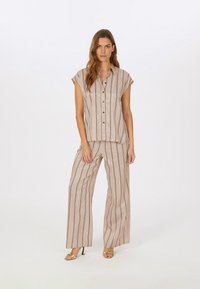 Beige gestreiftes Hemd und weite Hose, kurze Ärmel, Knöpfe vorne, glattes Material, mit schwarzen vertikalen Linien und lockerer Passform.