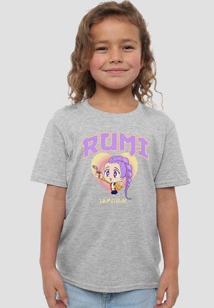 Smiling child with curly hair wearing a gray T-shirt featuring a purple-haired cartoon girl and the text "RUMI HUNTRIX."