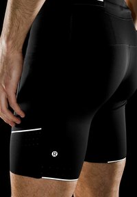 Sorte sportshorts med tætsiddende pasform, prydet med et hvidt logo, reflekterende detaljer og struktureret panel ved kanten. Glat stof.