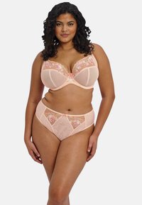 Perzikkleurig lingerie set met een doorzichtig, geborduurd bh met bloemenaccenten en bijpassende hoogwaist slipjes met patroon details en decoratieve afwerking.