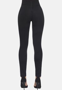 Czarne legginsy o dopasowanym kroju, wysokim stanie i gładkiej fakturze. Noszone z czarnymi, wysokimi szpilkami, podkreślają elegancką sylwetkę.