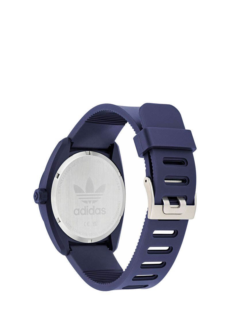 Vue arrière d'une montre-bracelet Adidas bleu marine avec fond de boîtier en acier inoxydable argenté et bracelet en silicone ajustable avec boucle.