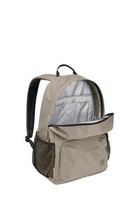 Sac à dos en tissu beige avec une fermeture éclair en haut, une poche avant et des poches latérales en mesh. À l'intérieur, il dispose d'une doublure argentée et d'une poche de rangement.