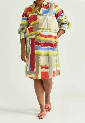 Kolorowa sukienka na guziki z wzorem patchworkowym w czerwone, niebieskie, żółte i zielone pociągnięcia na jasnym tle; długie rękawy, kieszenie.