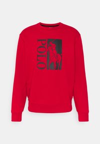 Czerwona bluza z okrągłym dekoltem, ściągaczami przy mankietach i u dołu. Na przodzie duży czarny motyw polo z napisem „POLO” obok. Miękka w dotyku.