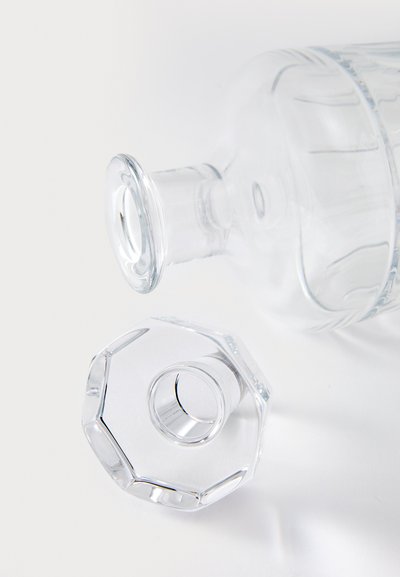 Klarer Glasdekantierer mit rundem Hals und achteckigem Verschluss, ausgestattet mit glatten Oberflächen und feinen vertikalen Linien zur Strukturierung.