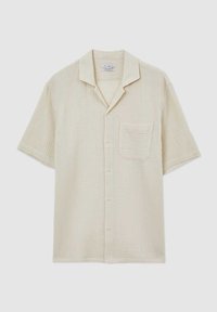 Chemise beige à manches courtes boutonnée, en tissu texturé, col camp et poche poitrine, présentée sur un fond uni.