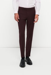 Maroon dress pants with a slim-fit design, featuring belt loops and side pockets, paired with black loafers, displayed on a neutral background.