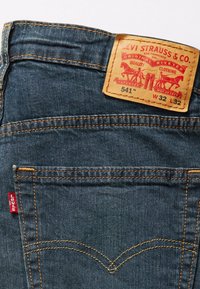 Poche arrière d'un jean en denim avec l'onglet rouge Levi's et un patch en cuir indiquant Levi Strauss & Co., taille W32 L32, modèle 541.